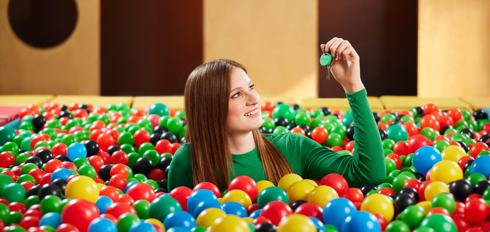 BTS image of a young model shooting in a big ball pool for a Chipolo commercial.